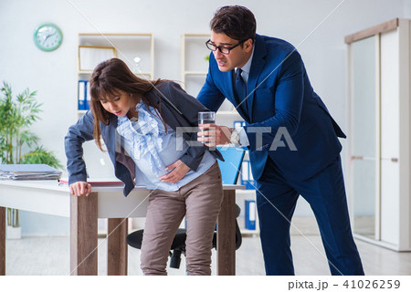 Pregnant woman struggling in the office and getting colleague he Pregnant woman struggling in the office and getting colleague he 41026259