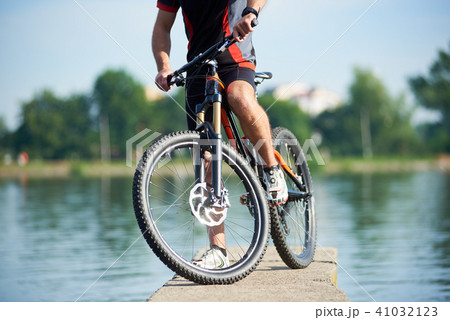 Crop of cyclist posing next to his bike 41032123