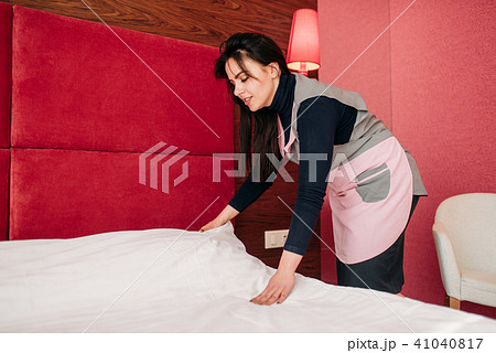 Pretty maid makes the bed in the hotel room 41040817