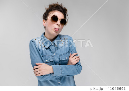 Young brunette girl in black glasses. Cat glasses. The hair is gathered in a bun. The girl shows her Young brunette girl in black glasses. Cat glasses. The hair is gathered in a bun. The girl shows her 41046691