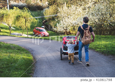 A father with toddler son pushing a jogging stroller outside in spring nature. A father with toddler son pushing a jogging stroller outside in spring nature. 41061798