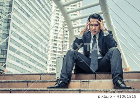 Young depressed businessman sitting on the stairs Young depressed businessman sitting on the stairs 41061819