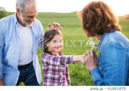 A small girl with her senior grandparents having fun outside in nature at sunset. 41061870