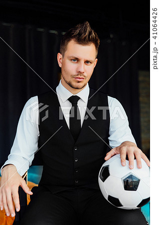 Stylish athletic man in a business suit and a soccer ball. Against the background of a loft wall. 41064426
