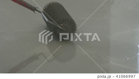 closeup using spike roller to remove air bubbles from self leveling floor 41066997