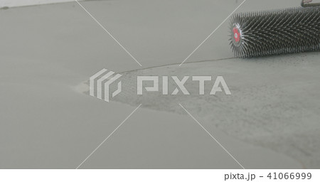 closeup using spike roller to remove air bubbles from self leveling floor 41066999
