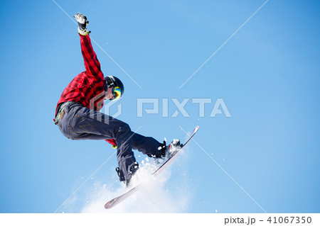 Photo of young sportive man jumping with snowboard 41067350