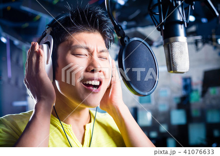 Asian male singer producing song in recording studio 41076633