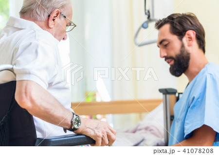 Elderly care nurse helping senior from bed to wheel chair  41078208