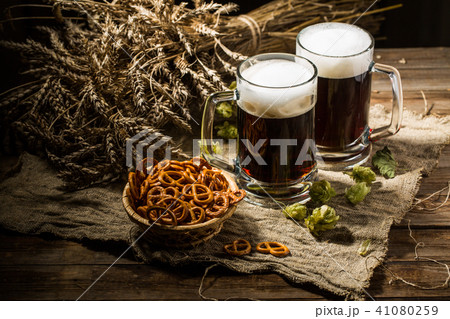 Two tankard beer with wheat and hops , basket of pretzels 41080259
