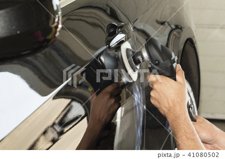 Car detailing - Hands with orbital polisher in auto repair shop. Selective focus. Car detailing - Hands with orbital polisher in auto repair shop. Selective focus. 41080502