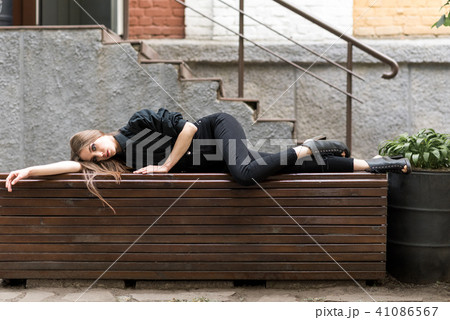 The girl is lying on the bench. The girl is lying on the bench. 41086567