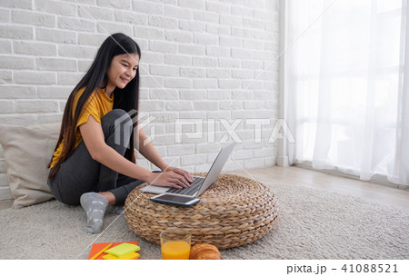 Asian female sit knees up on floor using laptop 41088521