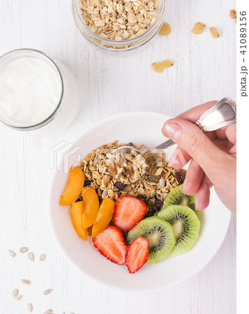 Top view of bowl with granola and woman's hand. Top view of bowl with granola and woman's hand. 41089156