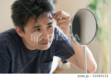 鏡を見て白髪を気にする中年男性 41094133