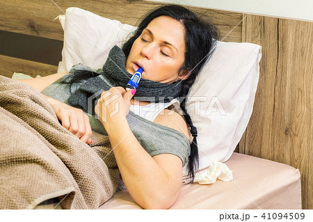 Sick woman keeping thermometer in mouth Sick woman keeping thermometer in mouth 41094509