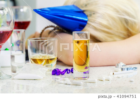Glass of alcohol with drunk sleeping woman behind 41094751