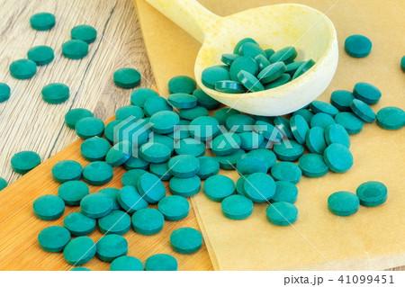 Spirulina tablets near wooden spoon 41099451