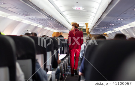 Interior of commercial airplane with stewardess walking the aisle. Interior of commercial airplane with stewardess walking the aisle. 41100067