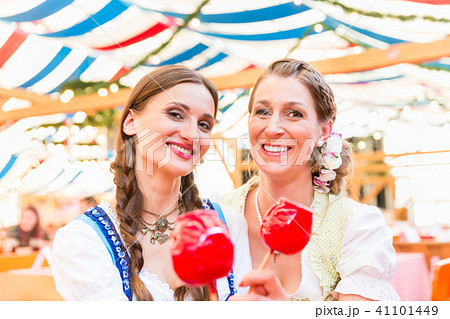 Friends in a beer tent holding candy apples Friends in a beer tent holding candy apples 41101449