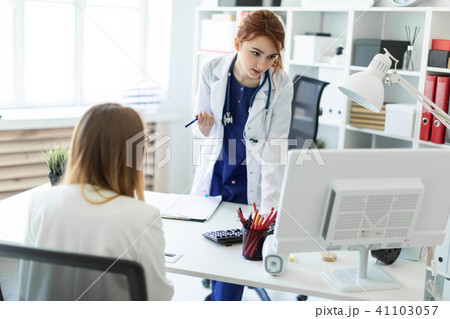 A beautiful young girl in a white robe is standing near a computer desk in the office and A beautiful young girl in a white robe is standing near a computer desk in the office and 41103057
