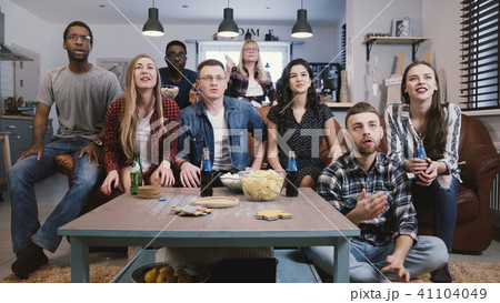 Mixed race friends watch sports on TV. Student football fans supporters get upset. Cheering for Mixed race friends watch sports on TV. Student football fans supporters get upset. Cheering for 41104049