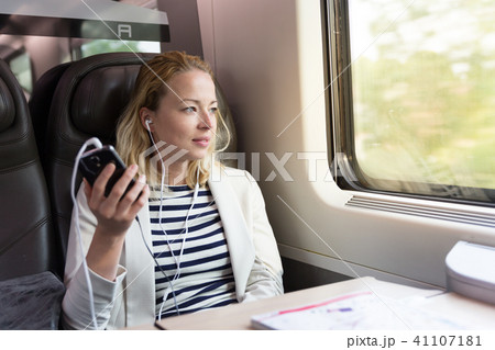 Businesswoman communicating on mobile phone while traveling by train. Businesswoman communicating on mobile phone while traveling by train. 41107181