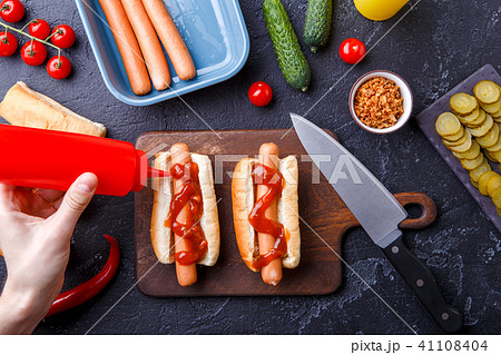 Picture on top of table with ingredients for hot dogs, cutting board, man's hands Picture on top of table with ingredients for hot dogs, cutting board, man's hands 41108404