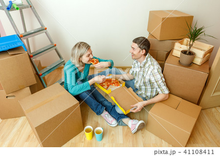 Photos of women and men eating pizza among cardboard boxes Photos of women and men eating pizza among cardboard boxes 41108411