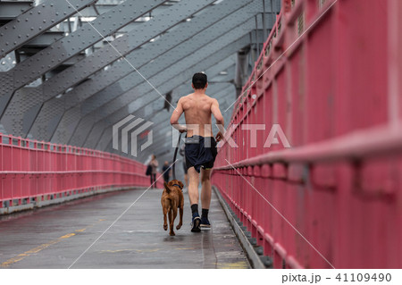 Unrecognizable topless recreational runner and a dog at Williamsburg bridgein New York CIty, USA. 41109490