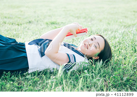 芝生に寝転がって本を読む高校生 41112899