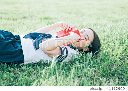 芝生に寝転がって本を読む高校生 41112900