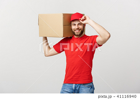 Deliver Concept: Young caucasian handsome delivery man holding a box on shoulder. Isolated over grey 41116940