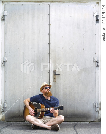 Man with fedora and cigar playing acoustic guitar 41119914