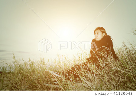 Sad young woman sitting on the grass feeling Sad young woman sitting on the grass feeling 41120043