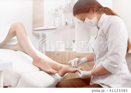 Brunette female podiatrist making polish and cleaning procedure  41123585