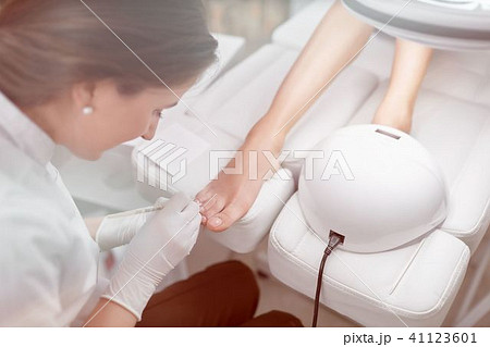 Specialist in beauty salon cleaning cuticle around nails on feet Specialist in beauty salon cleaning cuticle around nails on feet 41123601