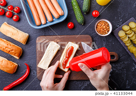 Picture on top of table with ingredients for hot dogs, cutting board, man's hands Picture on top of table with ingredients for hot dogs, cutting board, man's hands 41133044