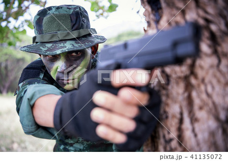 Private millitary holding gun aiming behind a tree 41135072