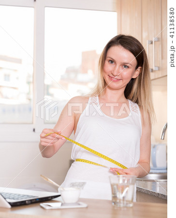 Portrait of sporty female who is standing and measuring waist Portrait of sporty female who is standing and measuring waist 41138580