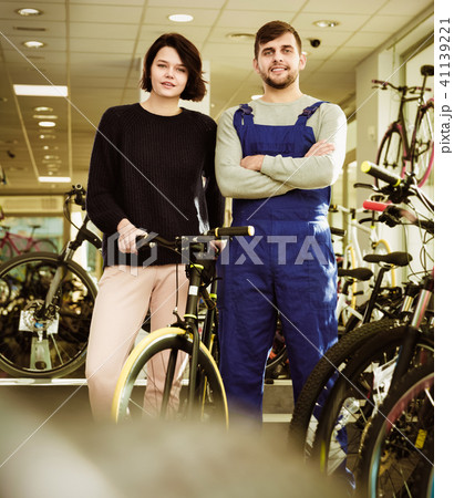 Young woman and seller standing with bicycle in the store indoor 41139221