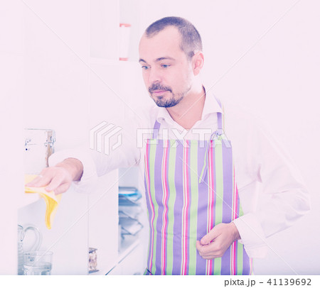 Young man in apron cleaning shelves 41139692