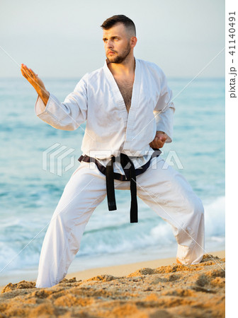 Guy doing karate poses at sunset sea shore 41140491