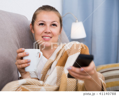 Young female is watching TV and sitting with tea Young female is watching TV and sitting with tea 41140788