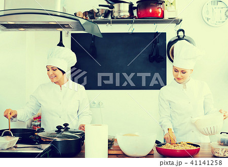 Two mature women chefs cooking food at kitchen 41141258