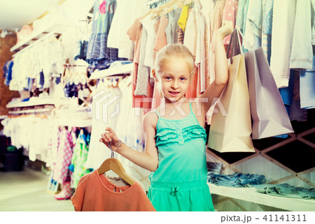 portrait of girl standing in kids clothes store with shopping b portrait of girl standing in kids clothes store with shopping b 41141311