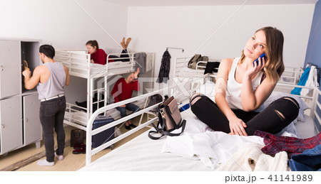 Woman talking on phone on bed in hostel Woman talking on phone on bed in hostel 41141989