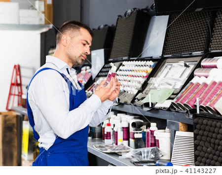 Professional car painter preparing paints for paintwork in modern auto repair shop 41143227