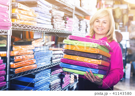 Woman showing stack of bedsheet in the textile shop Woman showing stack of bedsheet in the textile shop 41143580