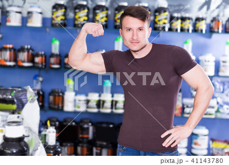 Young sportman demonstrating muscles in sport nutrition store 41143780